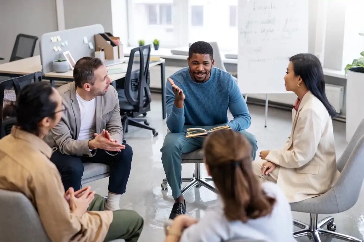 Diverse group participating in a mental health counseling and therapy session in a modern office, discussing emotional well-being and support