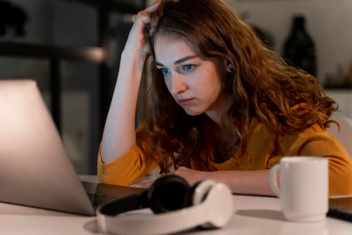 Woman feeling stressed while using a laptop at her desk, highlighting work pressure and mental exhaustion.