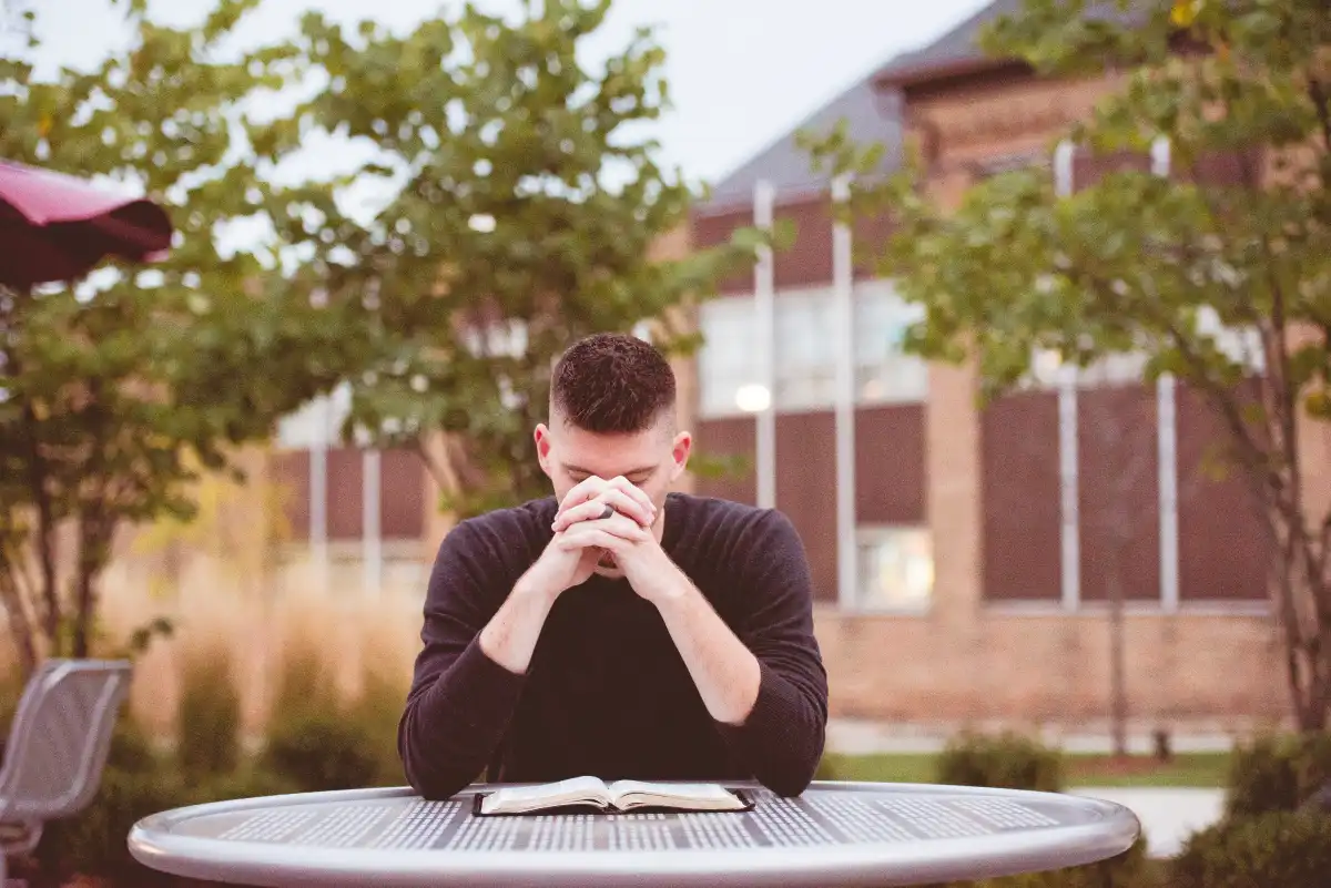 Young student sitting outdoors looking at a smartphone, highlighting the impact of social media and digital technology on youth mental health.