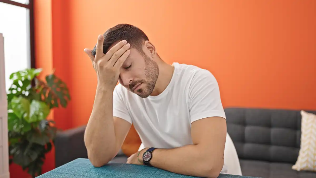 Man experiencing stress while sitting with his hand on his forehead
