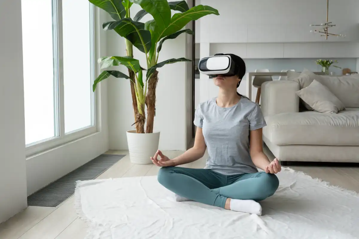 Person wearing a VR headset while sitting cross-legged and meditating at home, representing virtual reality wellness and mindfulness.